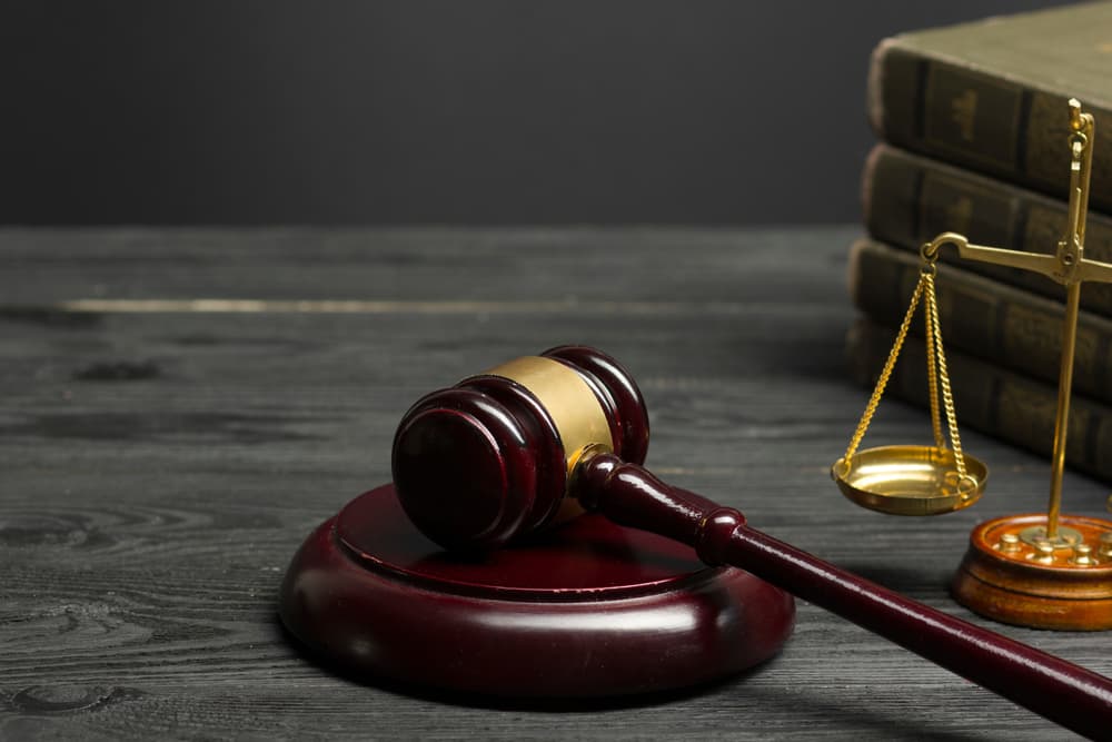 Judge’s gavel and scales of justice on desk representing legal court case and law.