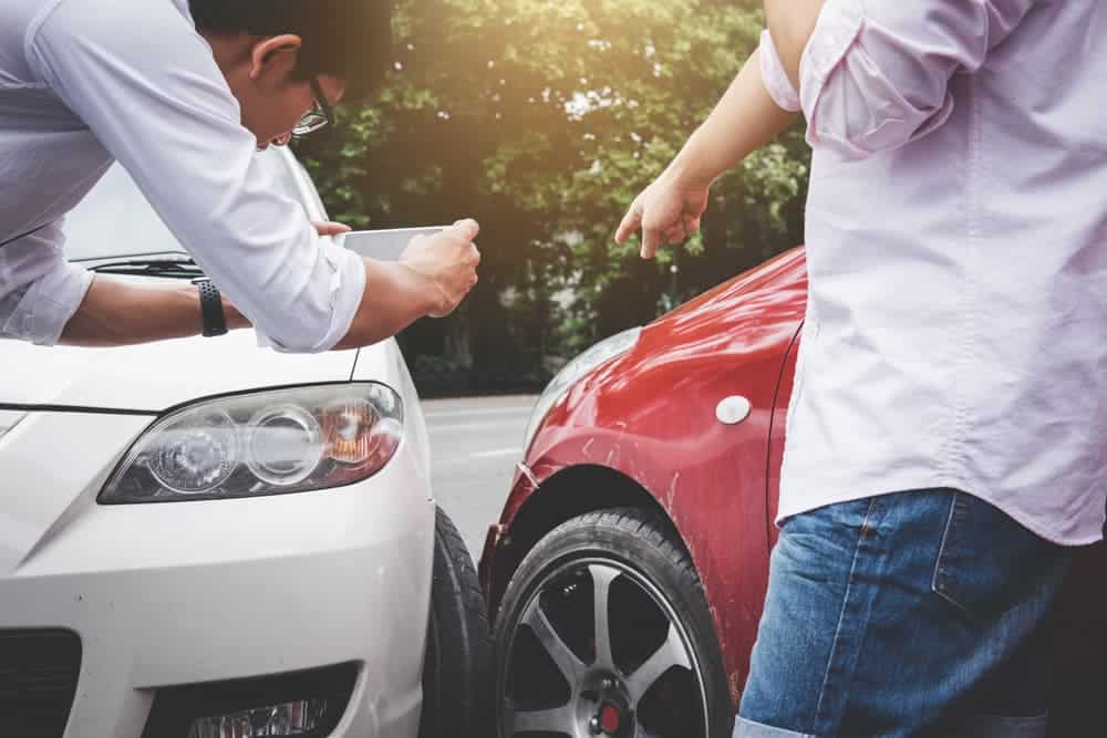 Two drivers arguing after a car accident, one making a phone call to an insurance agent. Traffic accident and insurance concept. Two drivers arguing after a car accident, one making a phone call to an insurance agent. Traffic accident and insurance concept.