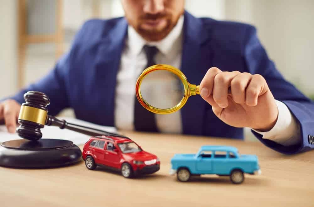 Car accident investigation with lawyer examining crash evidence using magnifying glass and model vehicles. Car accident investigation with lawyer examining crash evidence using magnifying glass and model vehicles.