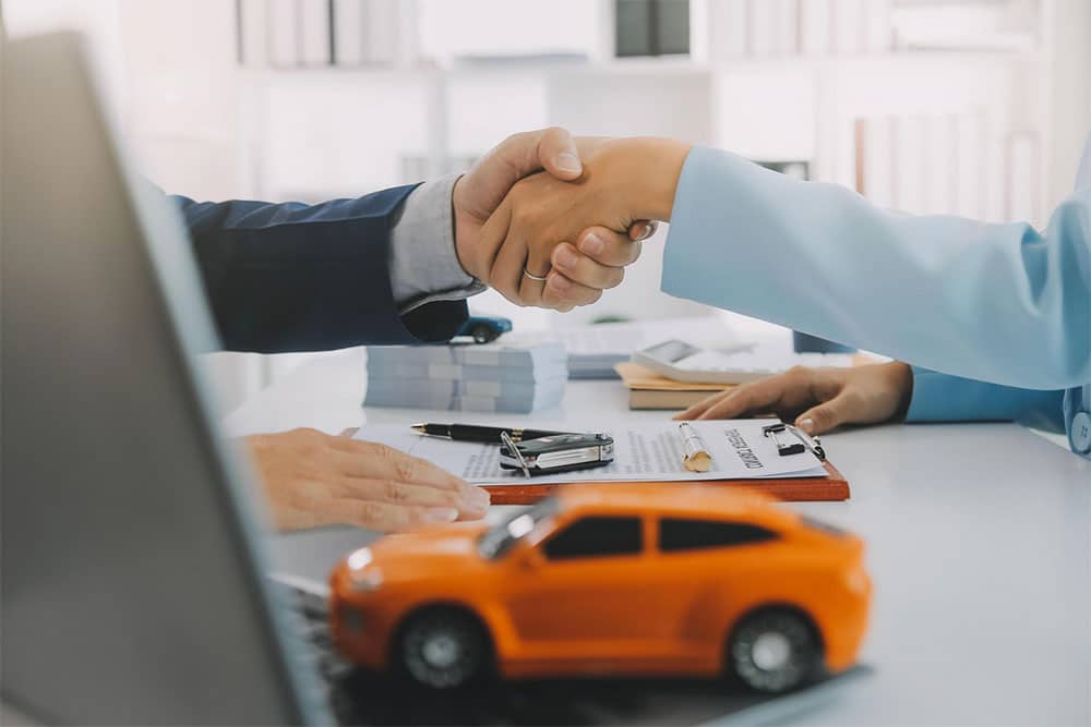 Car accident settlement agreement handshake between lawyer and client in office.