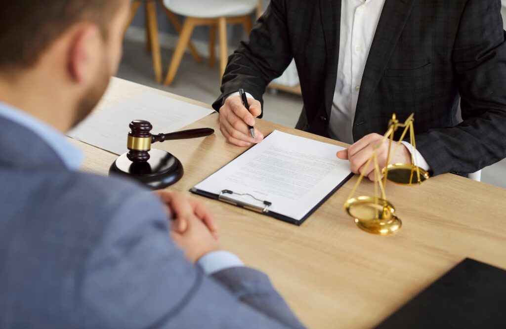 Client consulting with car accident lawyer in office reviewing legal documents after intersection crash